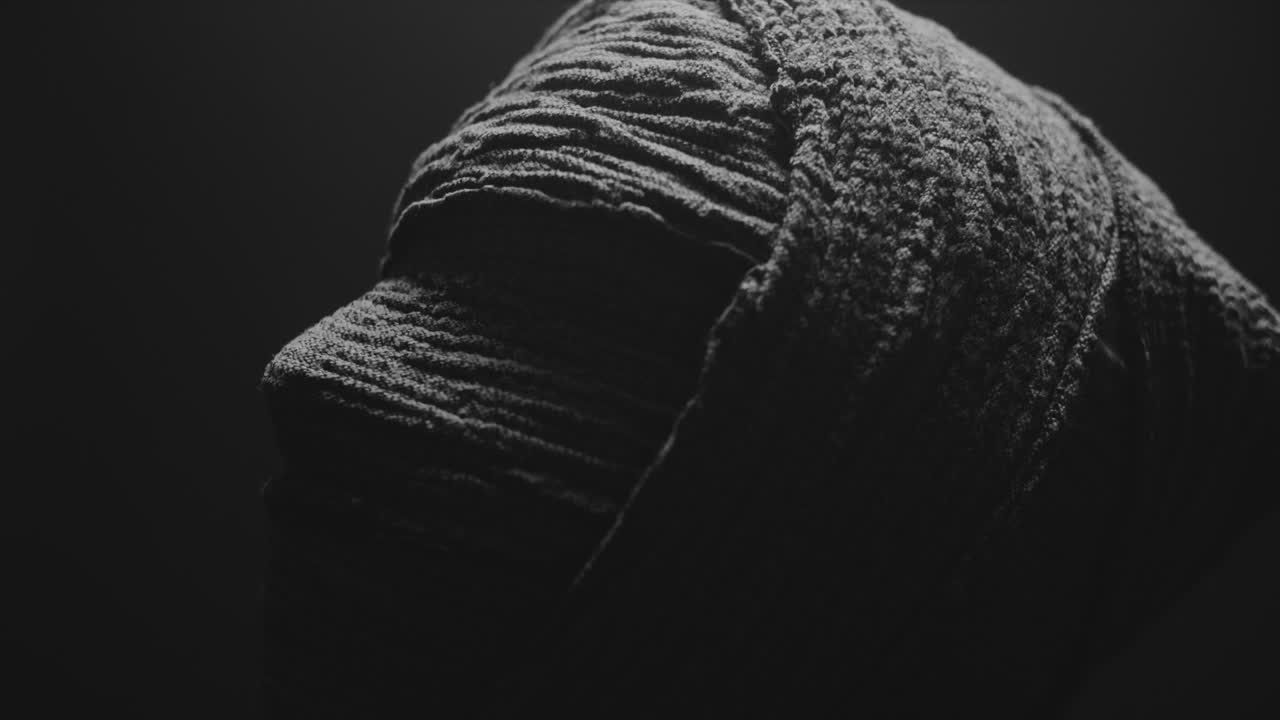 A mummy of a woman on a dark backdrop turns her head