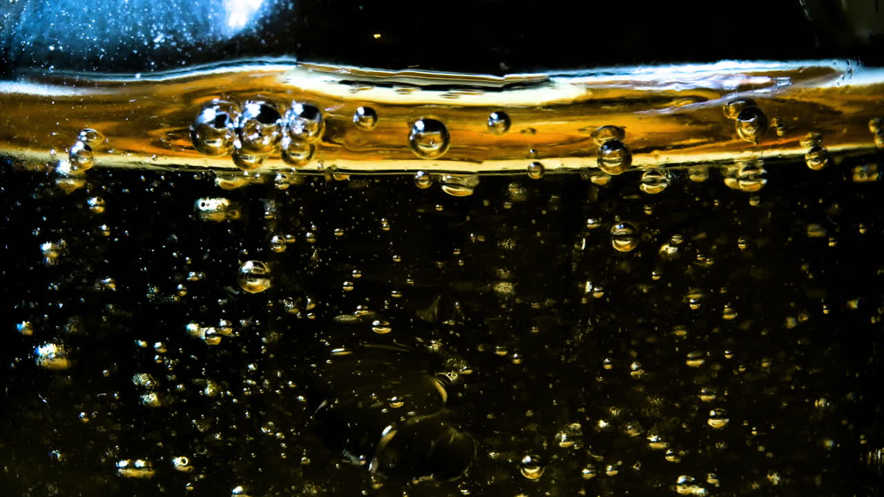 абстрактная золотистая жидкость с поднимающимися пузырьками на темном фоне