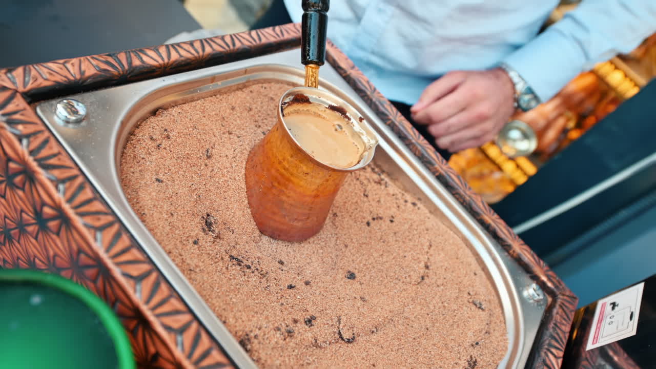 Turkish coffee preparation on hot sand, adding sugar cubes