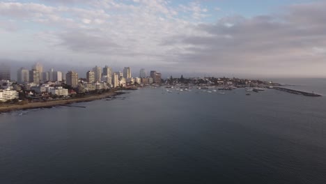 Luftpanoramaaufnahme-Der-Stadt-Punta-Del-Este-Mit-Sandstrand,-Skyline-Und-Hafen-Mit-Booten