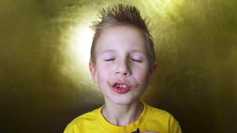 niño feliz comiendo una rosquilla de chocolate. niño comiendo comida chatarra. rubio disfruta de dulces.