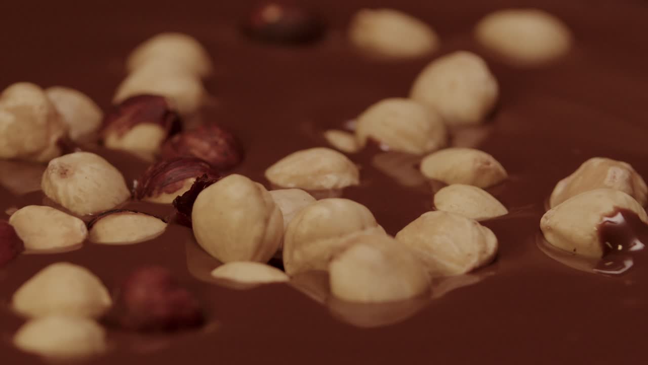 Nocciole che cadono nella cioccolata calda al rallentatore.