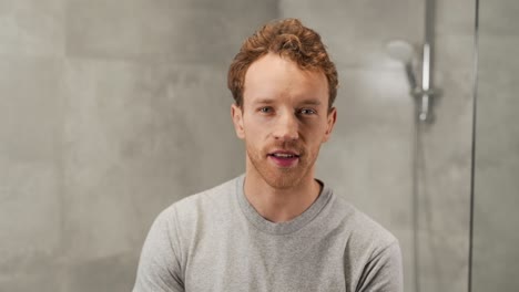 Cheerful-handsome-curly-man-applying-shaving-gel-with-his-hands