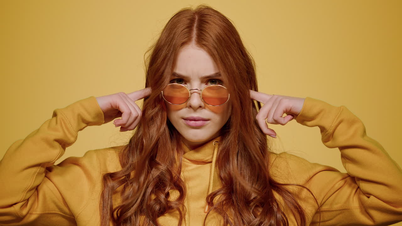 스튜디오에서 포즈를 취하는 흥분된 소녀. 오렌지색 배경에 귀를 닫는 여자