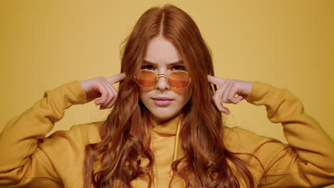 Agitated-girl-posing-in-studio.-Woman-closing-ears-on-orange-background