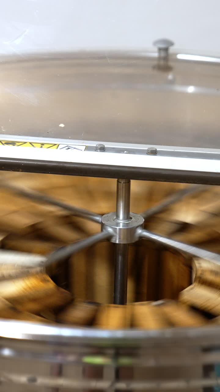 Working apparatus for extracting fresh honey. Rotating mechanism inside the metal bin full of honey frames. Vertical video