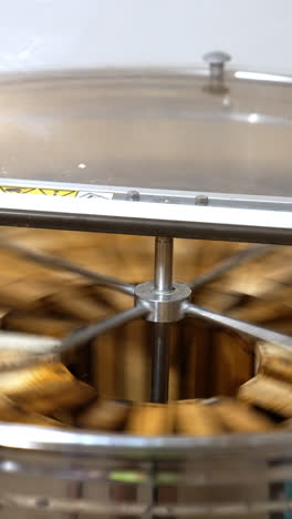 working apparatus for extracting fresh honey. rotating mechanism inside the metal bin full of honey frames. vertical video