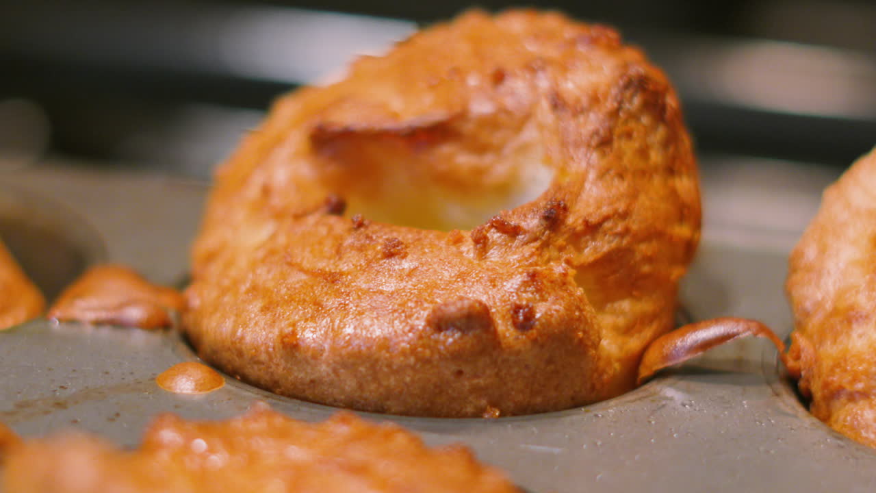 Close-up elegante de pudim Yorkshire britânico crocante e recém-cozido em assadeira. Perfeito para comerciais de alimentos de alto padrão, promoções de assado de domingo britânico e títulos de receitas de dar água na boca.