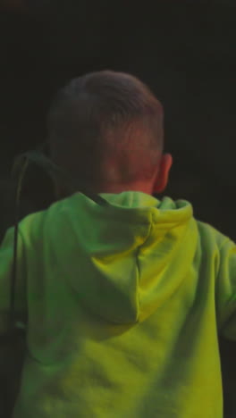 child walks alone in evening woods. little boy plays in high grass in nature park on vacation. active kid explores wild forest walking in evening