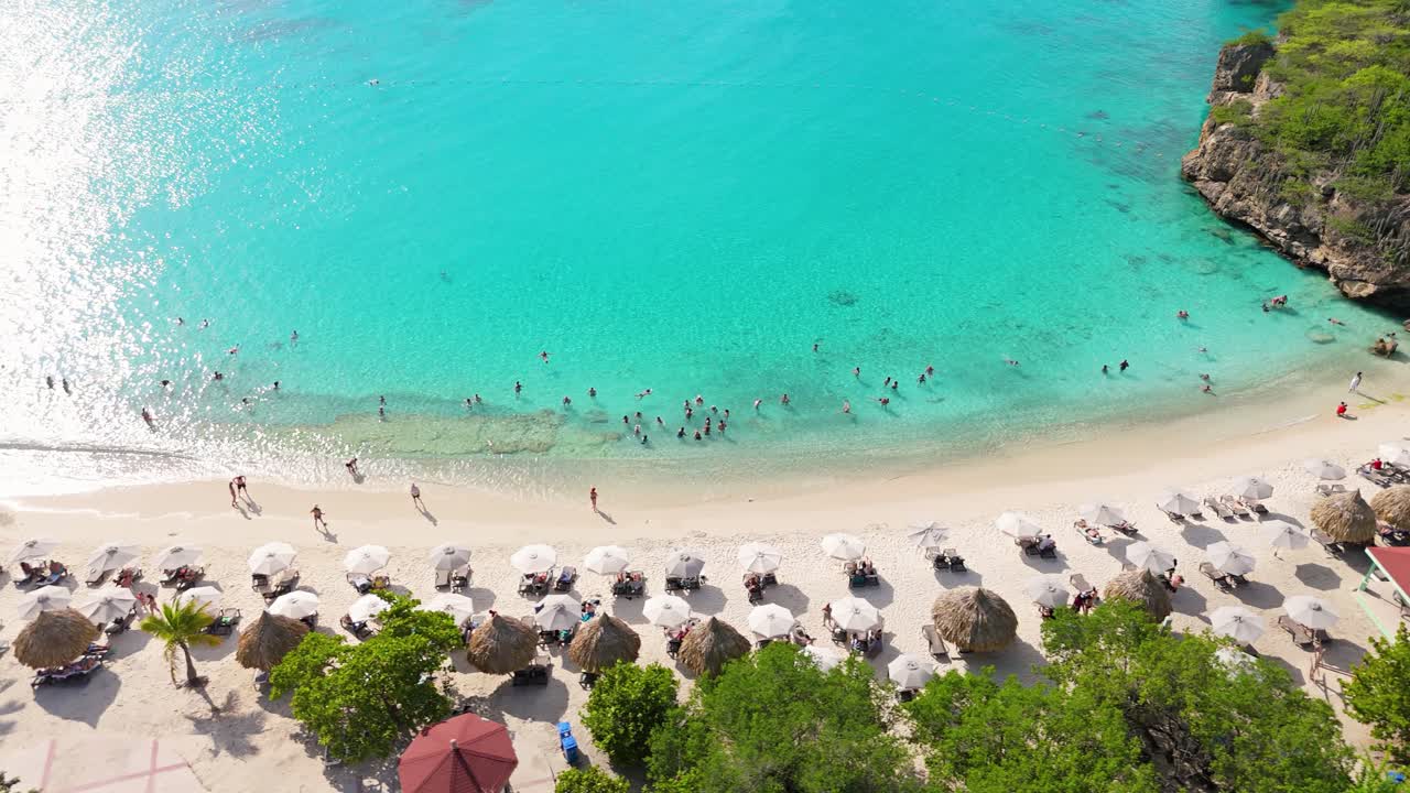 Vista dalla spiaggia verso il mare di sabbia bianca e turisti a Grote Knip, Curaçao