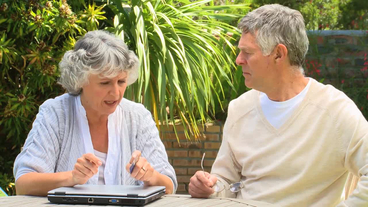 노트북 과 신용 카드 를 가지고 있는 부부 들 이 토론 하고 있다