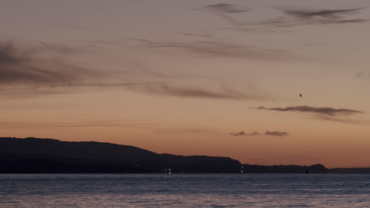 Serene Sunset over Ocean with Silhouetted Coastline