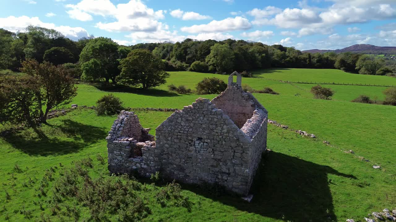 Lligwy chapel aerial view orbiting roofless medieval churchyard ruins on lush meadow farmland