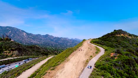 descending aerial view of hikers on mountain trail by freeway in los angeles