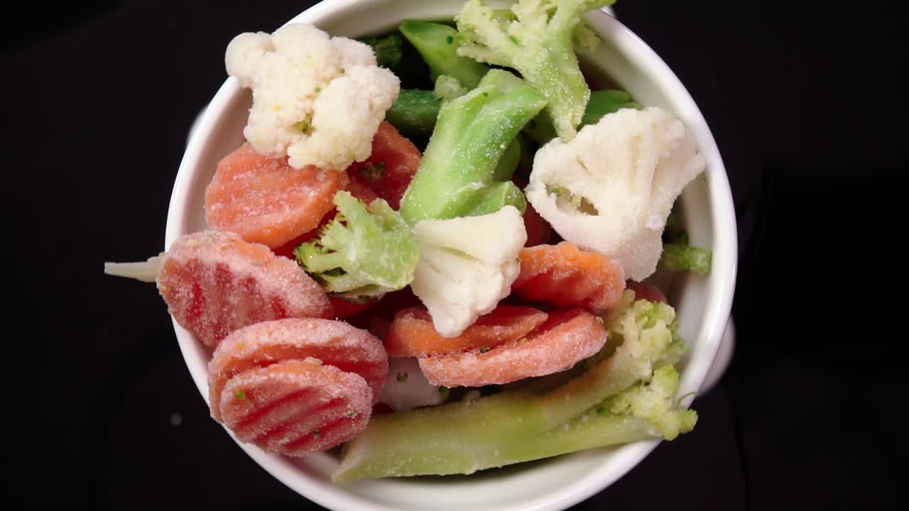 White bowl of frozen mixed vegetables like carrots, broccoli, and cauliflower