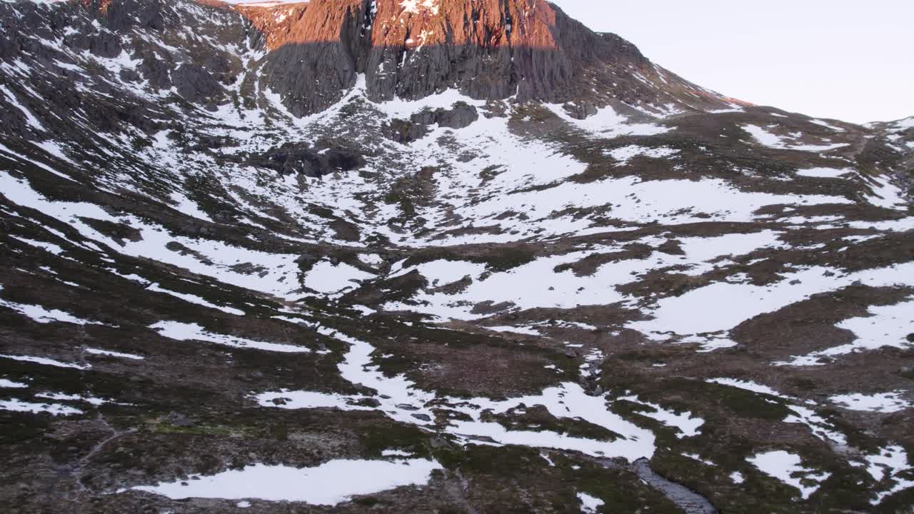 кадры, снятые с помощью беспилотного летательного аппарата, демонстрирующие мемориальный приют хатчисон и теплый восход солнца над драматическим вертикальным утесом, поднимающимся из снега и болота зимой