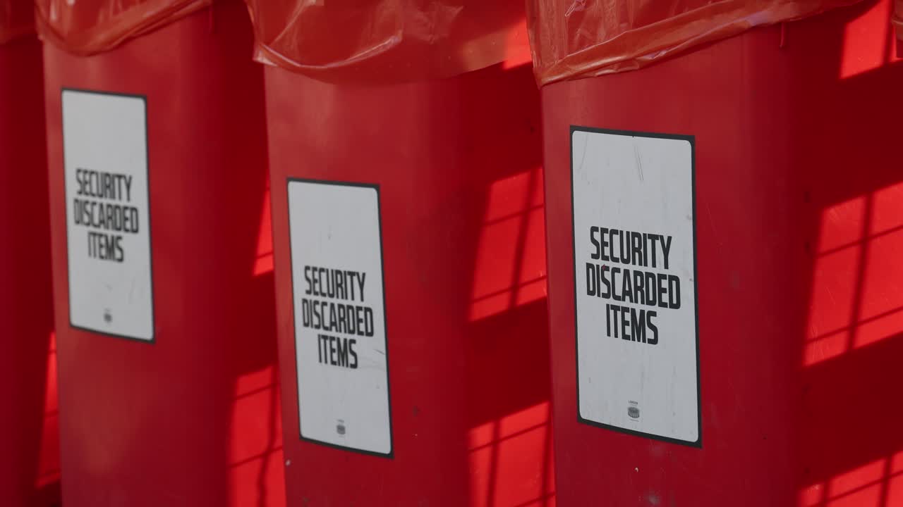 Cestino per oggetti scartati a un evento con sicurezza, articoli confiscati nella spazzatura.