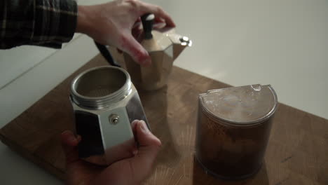 male opening a bialetti moka express coffee maker to put coffee ground in the filter in the morning