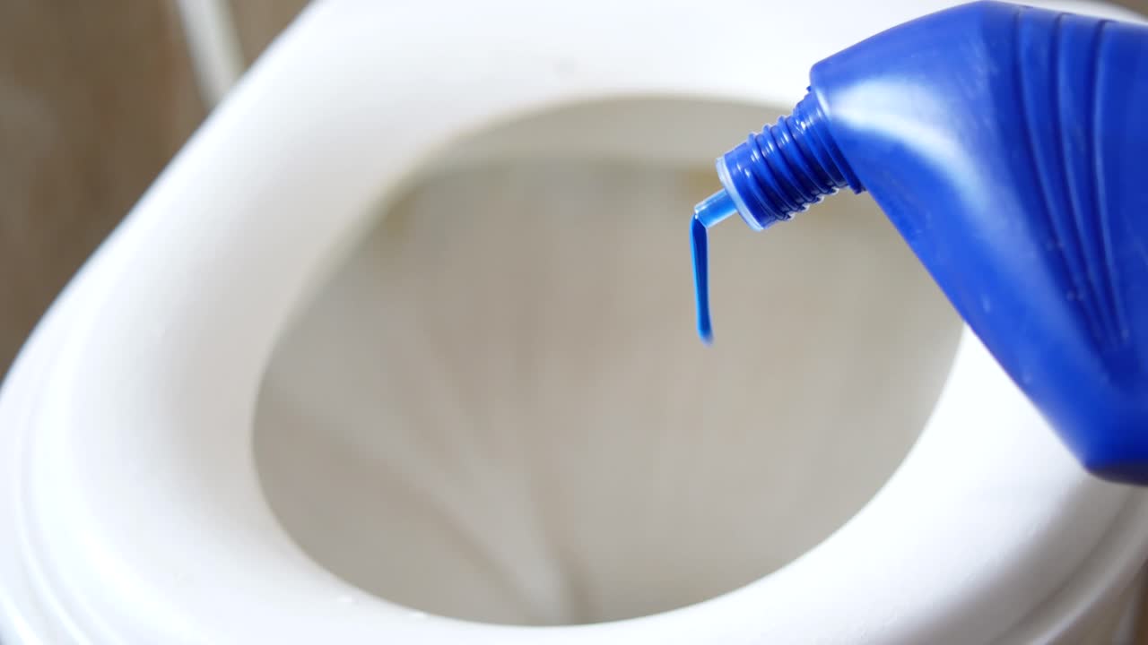 vertiendo limpiador de inodoro azul en un recipiente del inodoro