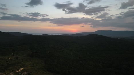 beautiful orange colored sky through the sunset over the silhouettes of the mountains on the tourist island of koh rong sanloem in cambodia. backwards drone dolly shot