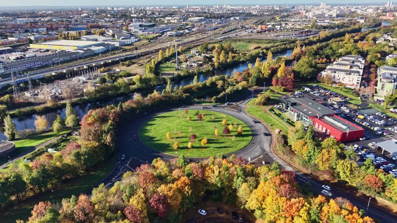Approaching drone fly to Cesson-Sévigné roundabout and city park surrounded by autumn trees and roads, Ille-et-Vilaine, Brittany, France