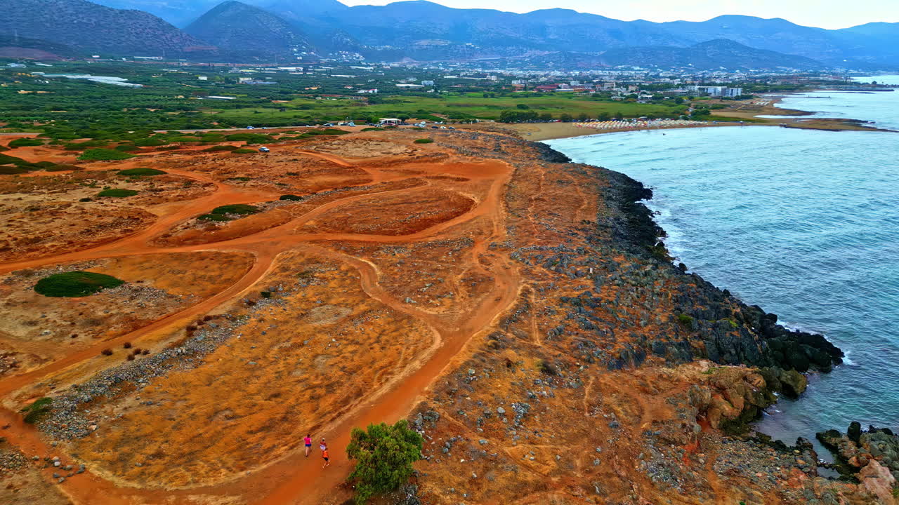 Moving drone shot of arid land and ocean on either side of Potamos Beach in Crete Island, Greece.