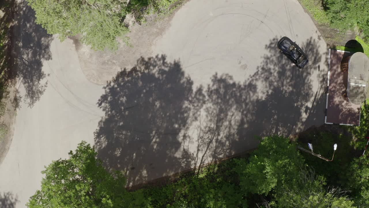 vista superior de despegue coche de carreras coche a la deriva en el círculo. coche japonés conduciendo con deriva en la carretera del campo. vista aérea viejo coche negro jdm girando con deriva