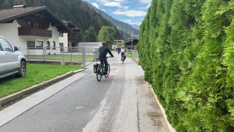 奧地利提羅爾的一條車道上騎單車的人, 展示一座村莊的房子