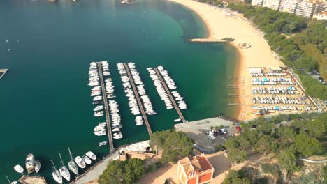 Luftbild-Von-Sant-Feliu-De-Guíxols-Vom-Hafen-In-Richtung-Hauptstrand-Mit-Der-Stadt-Im-Hintergrund