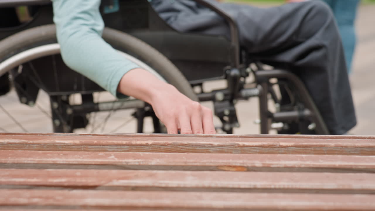 Closeup Of Man Touching Worn Wooden Bench, Caucasian Man Exploring Textured Wooden Slats With Fingers, Individual In Wheelchair Examining Detailed Weathered Surface Of Wooden Slats