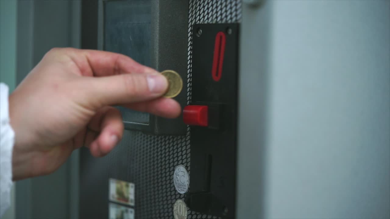 Hand inserting coin into a coin-operated machine