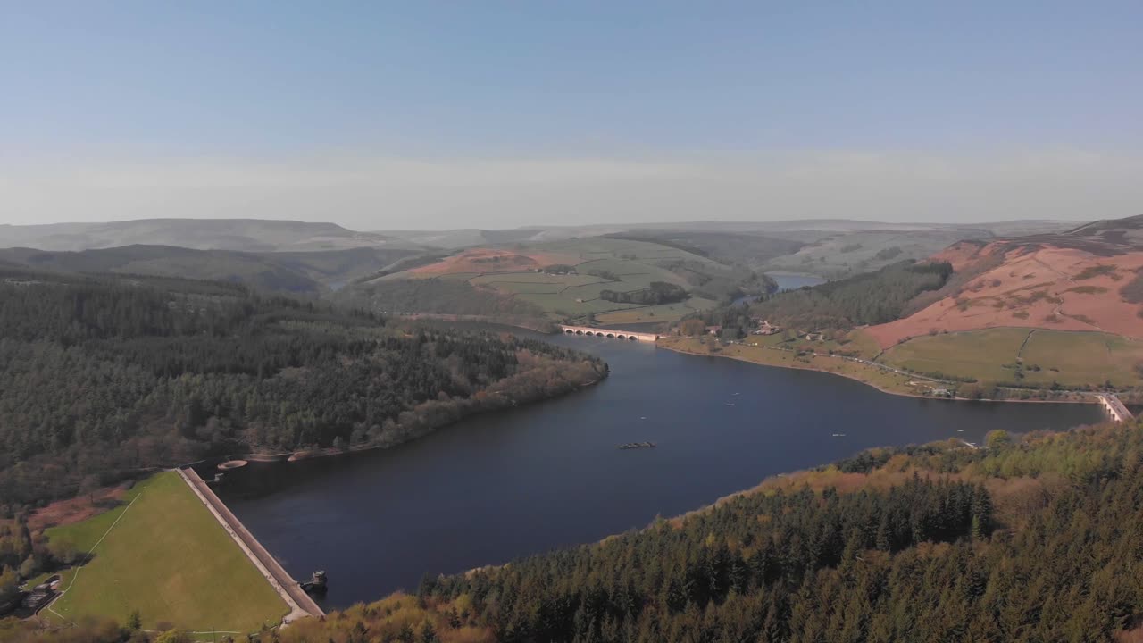 dron que se aleja del depósito de lady bower mientras se desplaza hacia arriba, revelando el depósito de lady bower desde un bosque cercano hacia el borde de bamford en el distrito de los picos, más corto, sin movimiento espasmódico, filmado en 4k