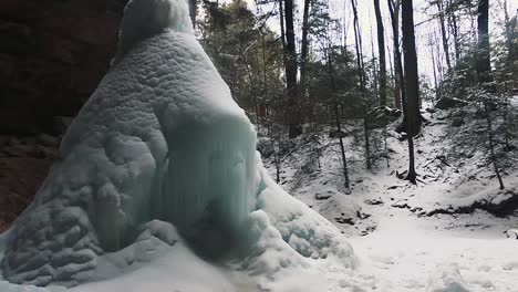 cono de hielo formado bajo la cascada congelada en la cueva de ceniza en invierno en el parque estatal hocking hills, south bloomingville, ohio