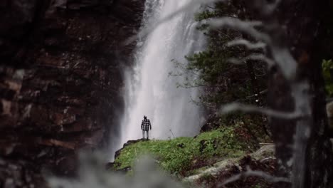 Man-standing-in-front-of-a-huge-waterfall,-reversed