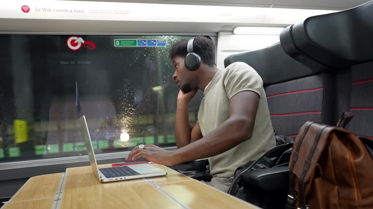 Man working on a laptop while traveling on a train