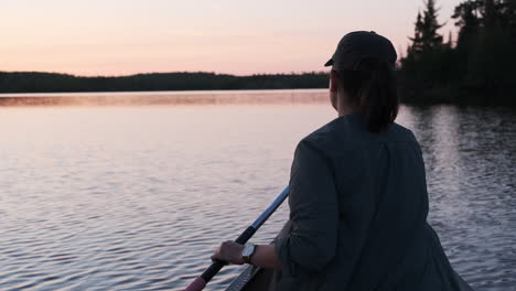 adventurous woman paddling in canoe at sunset