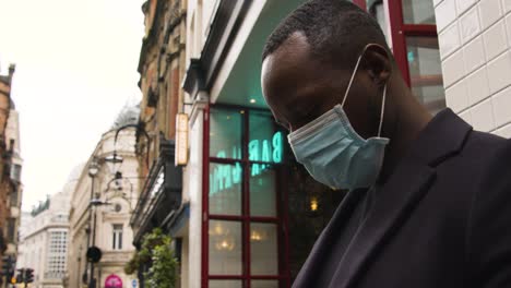 male wearing a medical mask looking around a busy street in london low angle