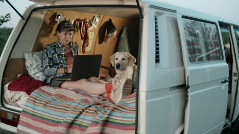 cheerful woman video calling on laptop in travel trailer