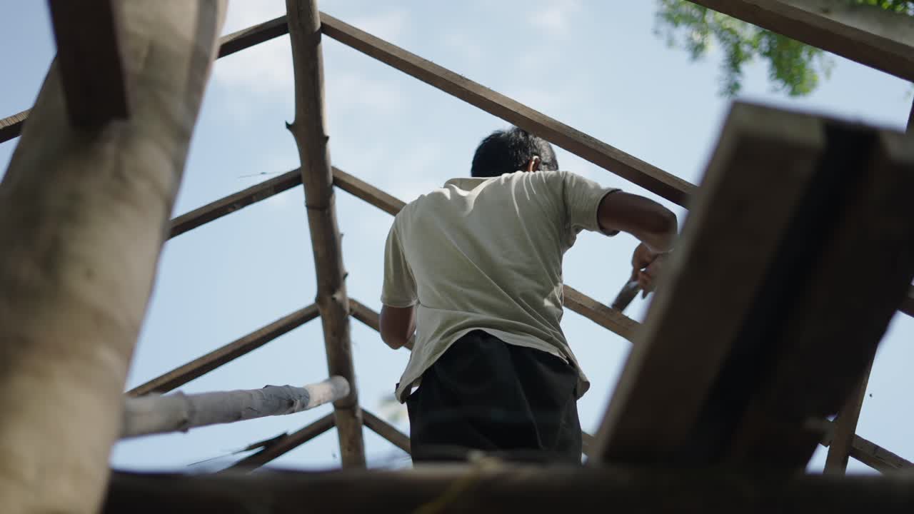 Man working on a wooden roof frame from below