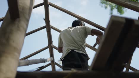 man working on a wooden roof frame from below
