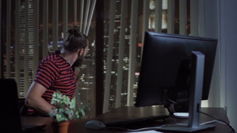 bearded man working in home office at night