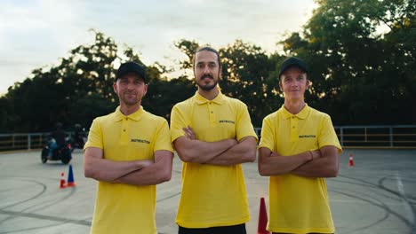 un equipo de instructores de conducción con una camiseta amarilla ponen las manos en el pecho y posan. trío de instructores en una escuela de conducción