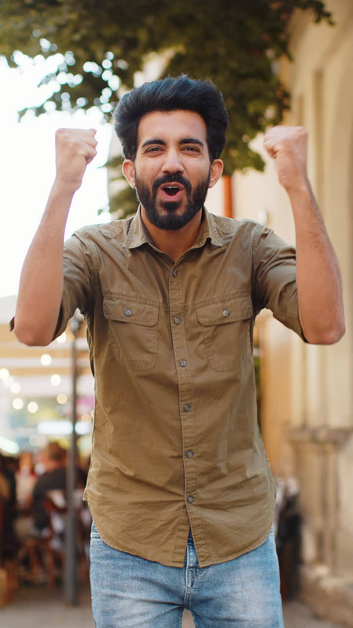 Young man shouting celebrating success winning goal achievement good victory news in city street
