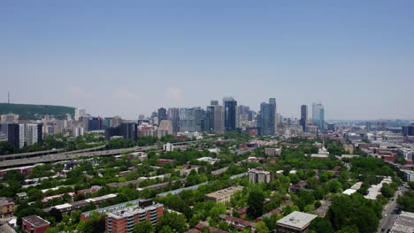 Drone-shot-ascending-in-front-of-suburbs-and-the-downtown-skyline-of-sunny-Montreal
