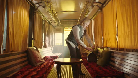man unpacking luggage in a vintage train carriage