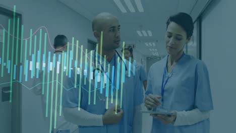 mid adult doctor gesturing stethoscope and nurse reviewing tablet in hospital hall with data graphs