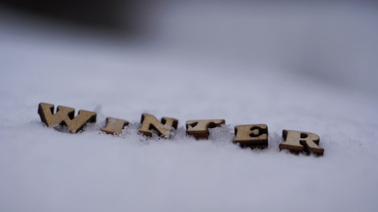 Close-up of letters spelling Winter as snow falls around
