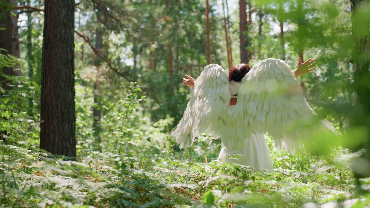 Fallen angel dressed in white spreads arms and prays to gods under warm sunlight surrounded by lush green forest, wings glowing softly as breeze moves leaves creating feeling of hope