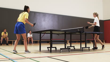 playing table tennis, two women competing in indoor sports facility