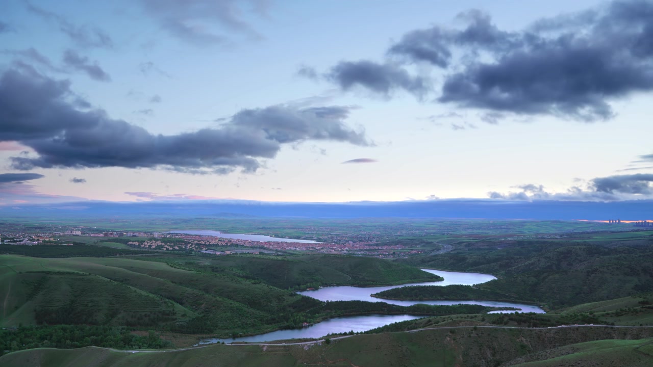 Aerial View of Winding River Through Green Hills at Sunset